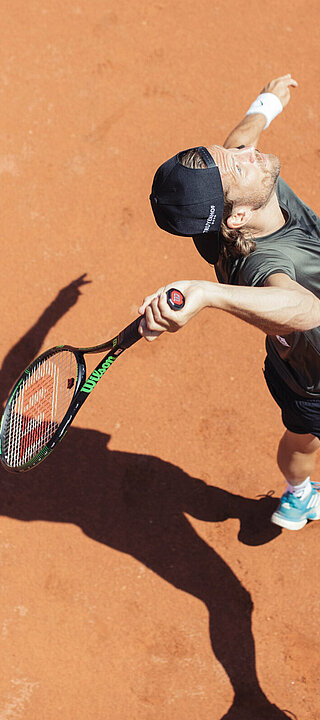 Mann beim Tennisspielen auf dem Tennisplatz im Hotel Truyenhof in Tirol