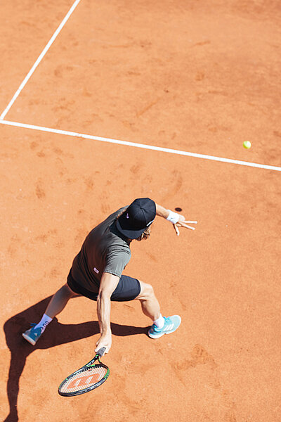 Mann beim Tennisspielen auf dem Tennisplatz im Hotel Truyenhof in Tirol