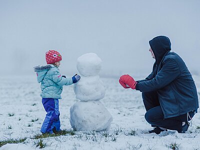 Mann und Kind bauen einen Schneemann in Ried in Oberinntal