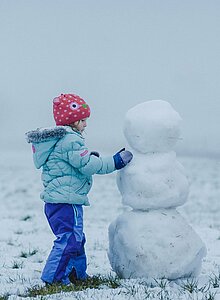 Mann und Kind bauen einen Schneemann in Ried in Oberinntal