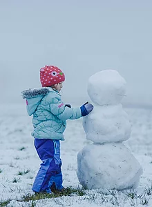 Mann und Kind bauen einen Schneemann in Ried in Oberinntal